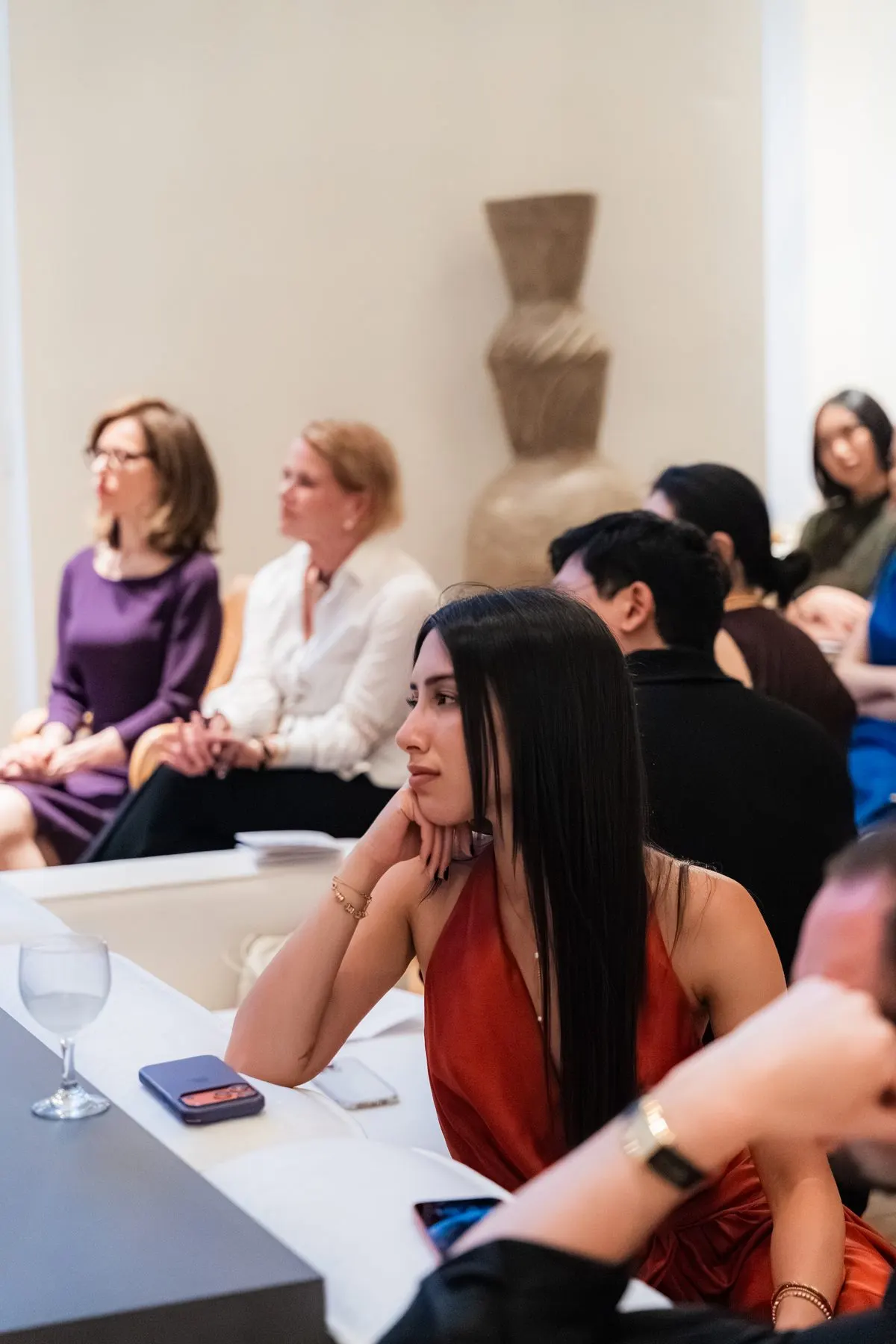 A guest listening, chin on her hand, the room behind her