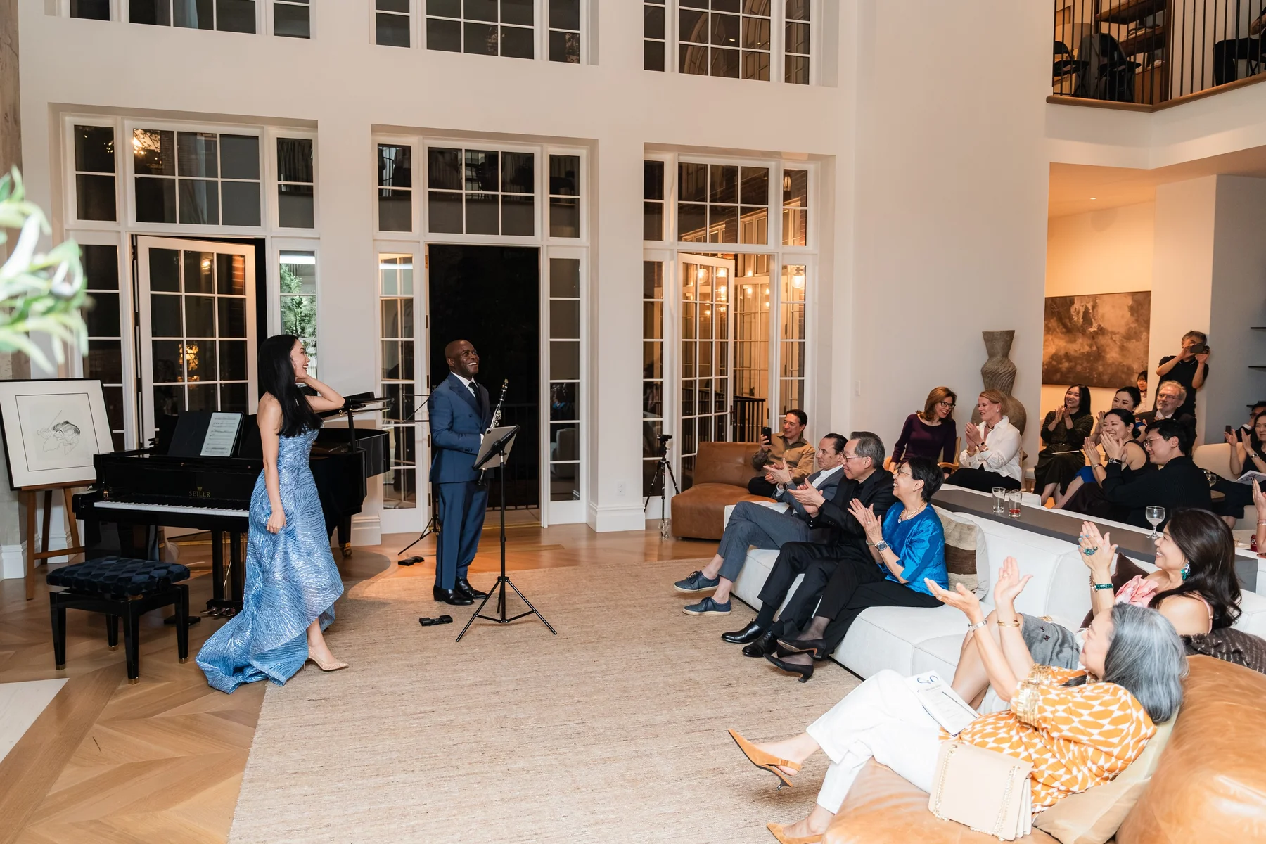 Rieko Tsuchida and Anthony McGill at the piano, the room applauding from the sofas