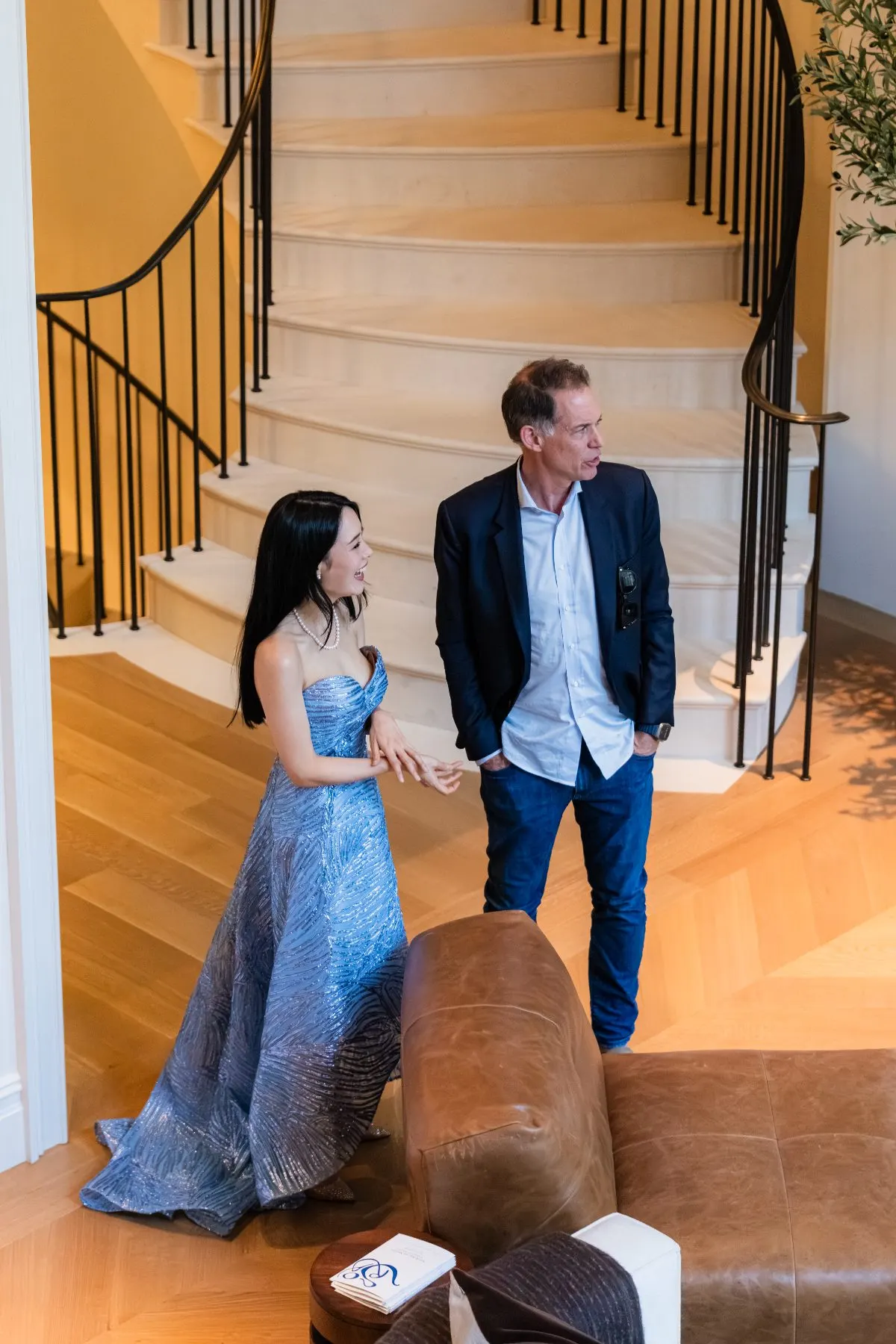 The pianist in a blue gown with a guest by the staircase
