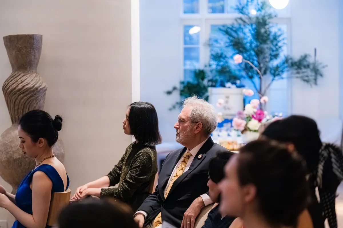 Guests listening in the townhouse salon, the ikebana and the window behind them